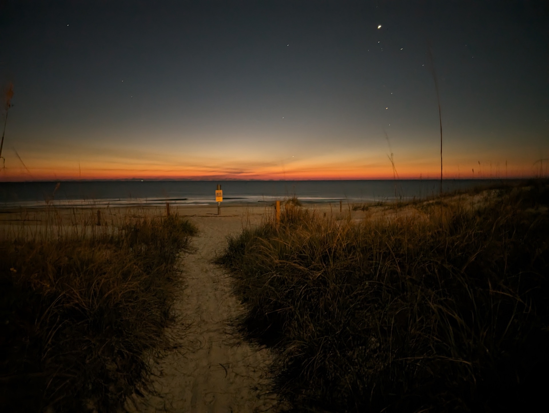 Sandy path through dune grass leading to the Atlantic Ocean at twilight with stars visible