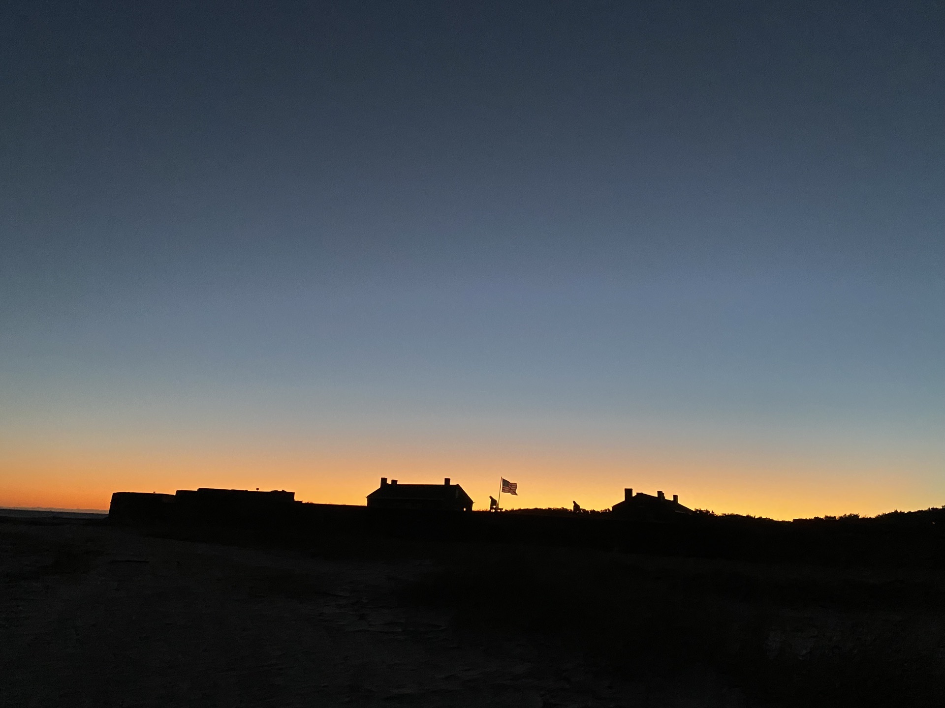 Fort Clinch silhouetted against a golden sunset sky with American flag flying